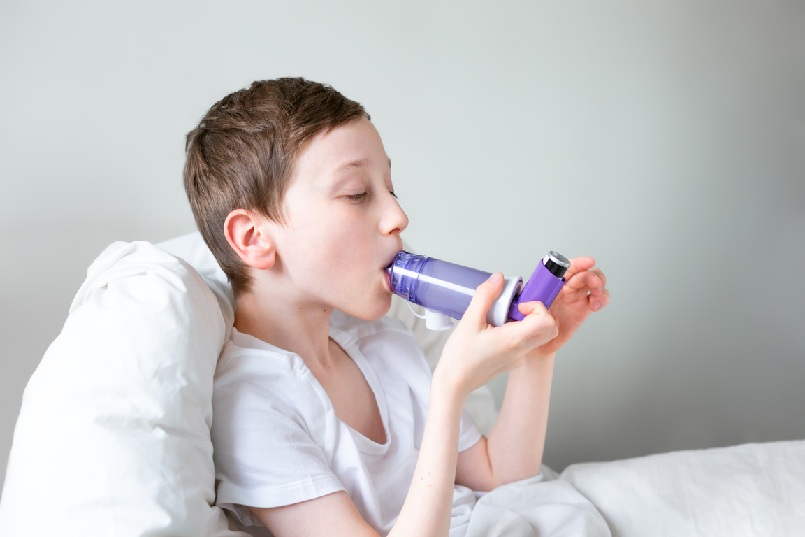 Kid having asthma allergy using the asthma inhaler.